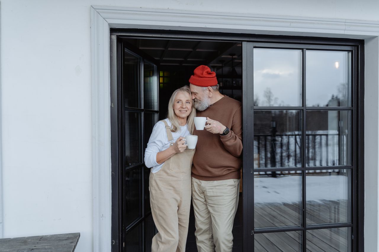 Happy senior couple enjoying coffee together outdoors, embracing lovingly.
